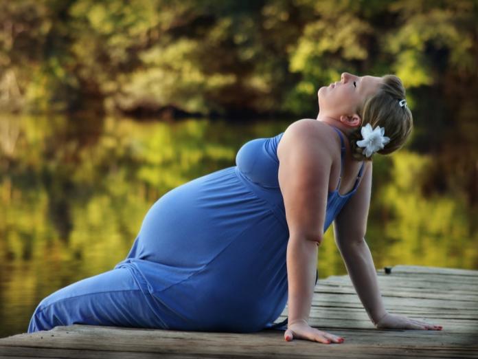 En gravid kvinde sidder på jorden og nyder naturen. 