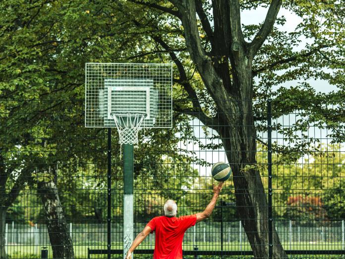 En mand er ved at kaste en bold op i en basketball-kurv. 